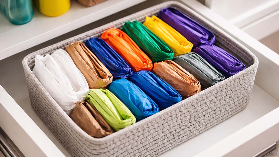 Platzsparend gefaltete Einkaufstüten als kleine Päckchen ordentlich in einer Box verstaut – einfacher Ordnungstipp für mehr Struktur im Haushalt, Schrank oder Vorratskammer.